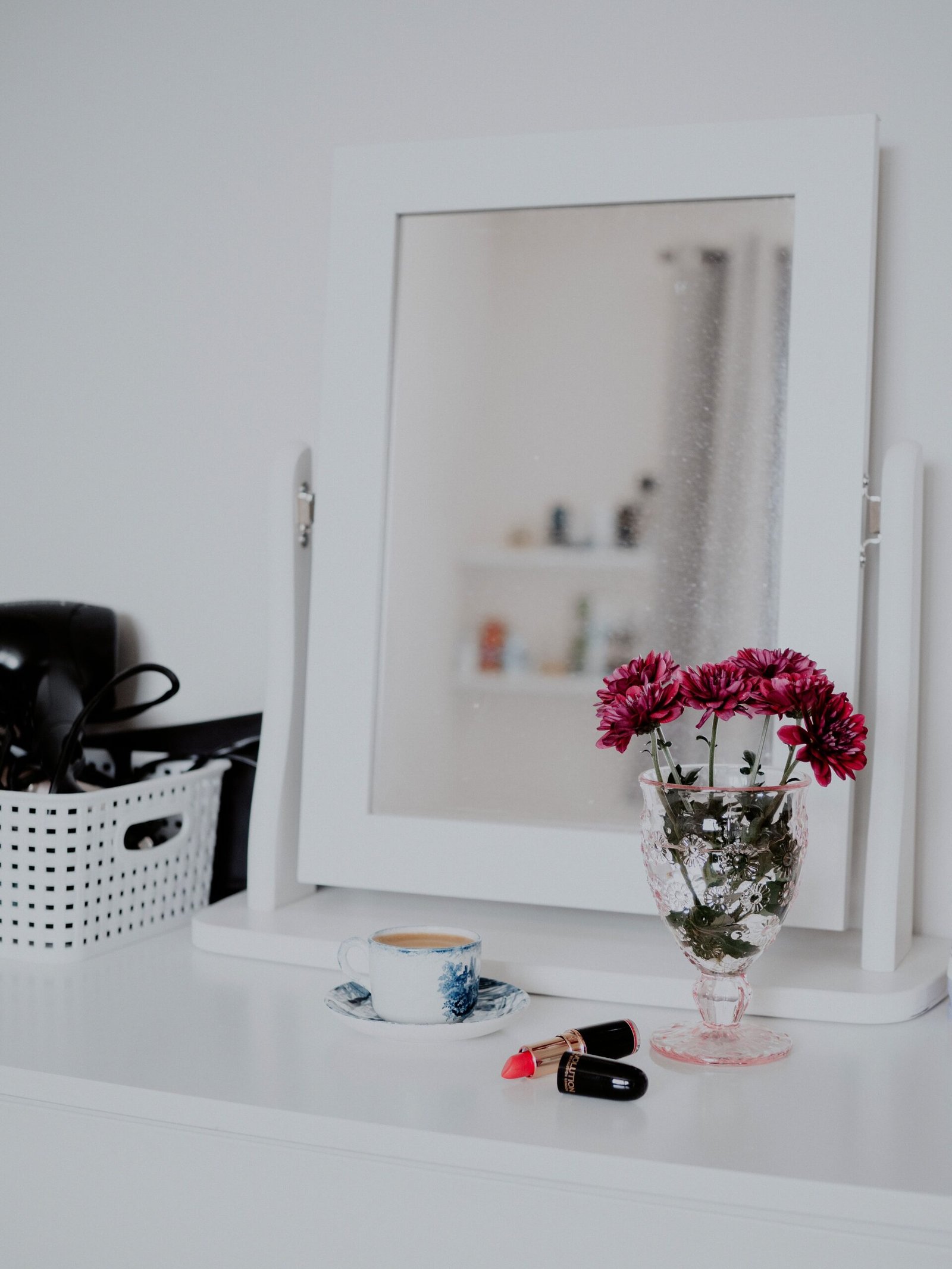 Styled dressing table surface with a mirror, fresh flowers and a few beauty essentials